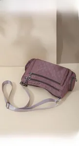 Macro view of purple quilted nylon crossbody bag showing multiple zippers and stitch detail