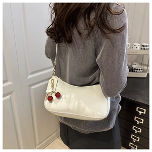 Détail du sac hobo en cuir verni blanc brillant avec pendentif cerise rouge