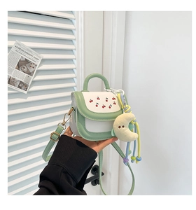 Detail of mint green and white mini bag with cherry print and moon plush charm