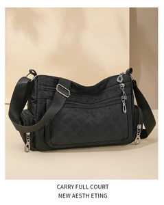 Detail of black quilted crossbody bag with multiple zippers and silver metal hardware
