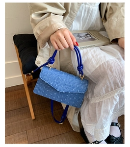 Détail du sac bandoulière en denim bleu avec texture effilochée et poignée en corde