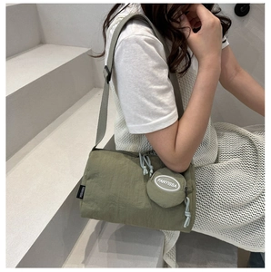 Detail of green cylinder nylon crossbody bag with small round coin purse and logo tag
