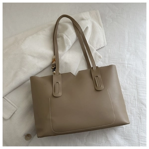 Detail of khaki leather tote bag featuring a V-shaped top cut and elegant floral scarf decoration