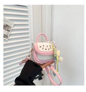 Detail of pink and white crossbody bag with cherry embroidery and plush toy charm