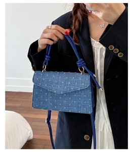 Détail du sac à main carré en denim bleu avec bords effilochés et poignée en corde nouée
