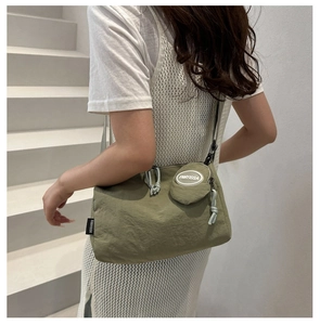 Detail of olive green nylon crossbody bag with small round coin purse on shoulder strap