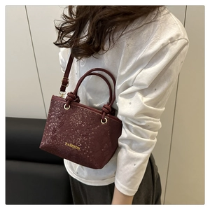 Sac seau rouge foncé à motif serpent porté en bandoulière par un mannequin femme