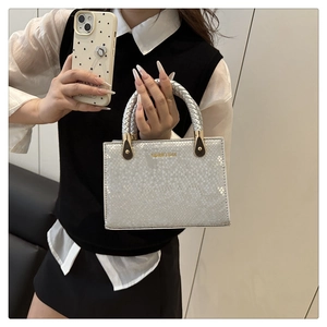 Detail of silver stone-patterned handbag with woven handle and gold hardware