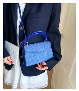 Gros plan du sac bandoulière bleu avec poignée nouée et texture à pompons en relief