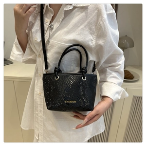 Vue détaillée de la texture serpent noire et du logo doré sur ce sac à main tendance