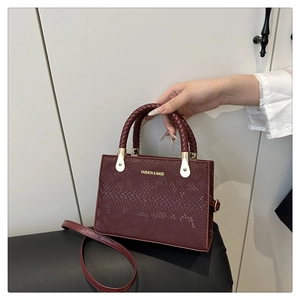 Close-up of wine red snake-skin crossbody bag with braided handles and gold metal hardware