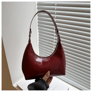 Détail du sac à bandoulière en cuir verni bordeaux brillant avec boucle en métal argenté