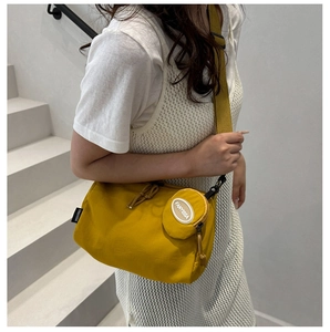 Detail of yellow nylon crossbody bag with matching round coin purse on a wide shoulder strap