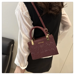 Detail of stone pattern texture and woven handle on a burgundy crossbody bag