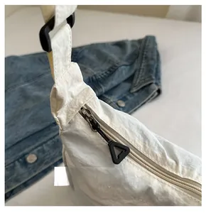 Dettaglio della cerniera argentata e tessuto in nylon della borsa a tracolla bianca