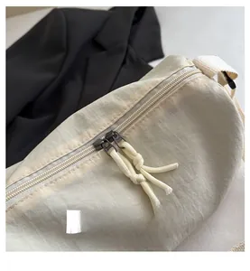 Close-up of smooth dual zippers with cream woven pullers on a beige textured nylon bag