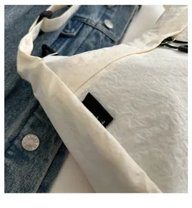 Dettaglio della borsa a tracolla in nylon bianco con etichetta FANYISSA e cinturino nero
