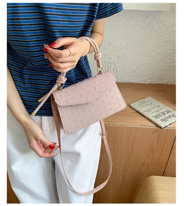 Gros plan du sac à bandoulière rose avec broderie à pois et poignée à nœud