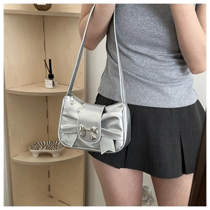 Detail of silver pleated baguette bag with large bow and metallic buckle clasp
