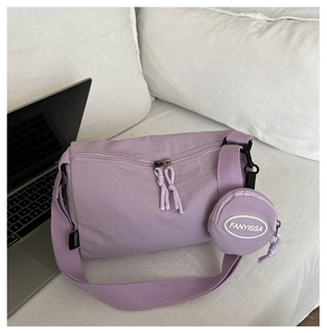 Detail view of purple nylon crossbody bag with matching round coin purse and brand label