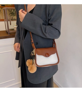 Detail of color-block crossbody square bag with brown pompom charm on a model