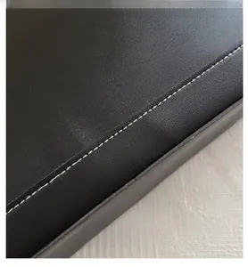 Detailed view of black leather tote bag with contrast white double stitching and clean edges