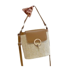 Straw woven bucket bag with brown leather flap and round gold metal clasp