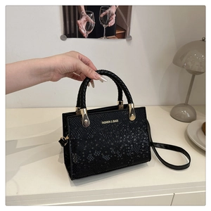 Detail of black faux leather crossbody bag with stone texture and gold hardware accents
