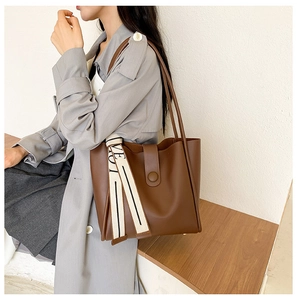 Close-up of caramel leather tote bag featuring a stylish printed silk scarf on the handle