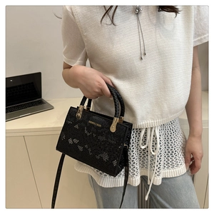 Detail of black faux snakeskin crossbody bag with gold FASHION & BAGS logo text