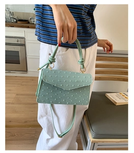 Détail du sac rectangulaire vert clair avec texture gaufrée et poignée ronde nouée
