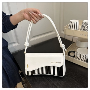 Détail du motif clavier de piano sur sac bandoulière en PU blanc avec lettrage doré