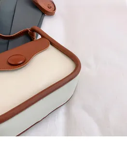 Detail of retro small square bag showing brown contrast trim and decorative button