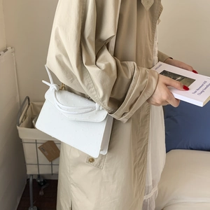 Gros plan sur un sac à main blanc motif autruche avec des détails de nœuds décoratifs