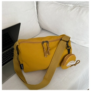 Close-up of mustard yellow nylon crossbody bag with mini coin purse on white bedding