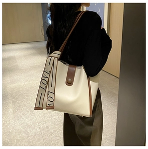 Detail of contrast stitch tote bag featuring a decorative LOVE canvas strap on a model