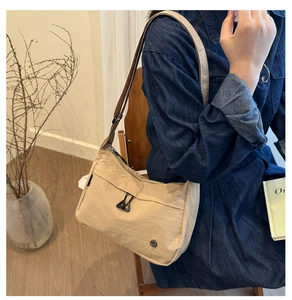 Dettaglio borsa tote beige in nylon con clip in metallo nero e tracolla regolabile