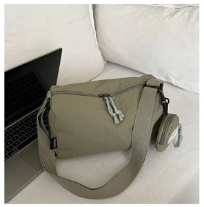 Olive green nylon shoulder bag detail with matching small round coin purse on white sofa