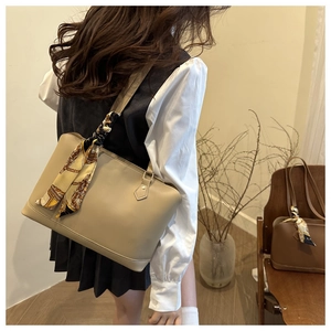 Detail of beige tote bag with decorative silk scarf and smooth faux leather texture