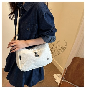 Dettaglio della trama in nylon bianco impermeabile e del logo sulla borsa a tracolla