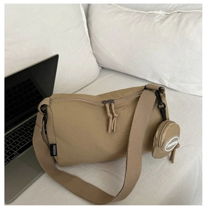 Macro detail of khaki nylon shoulder bag with woven strap and small round coin purse