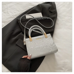 Detail of silver snake-patterned crossbody bag with gold hardware and dual handles