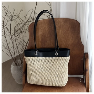 Detail of a large straw tote bag with black leather stitching on a vintage chair