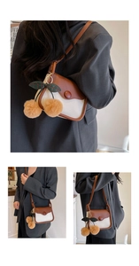 Detail of minimalist contrast shoulder bag with a plush cherry charm on a model