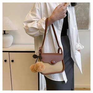 Detail of two-tone shoulder bag with cherry charm in a modern interior setting