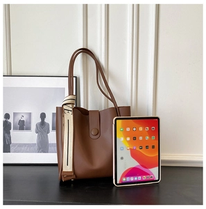 Detail of dark brown leather tote bag with white VE logo shoulder strap and flap closure