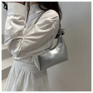 Borsa a mezzaluna metallizzata argento indossata da una modella in stile minimalista