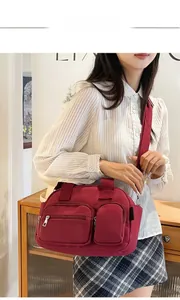 Détail d'un grand sac à bandoulière bordeaux avec plusieurs poches et sangle en tissu