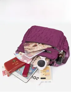 Detail of large purple nylon shoulder bag showing spacious interior with multi-pocket layout