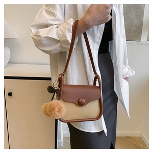 Detail of vintage crossbody bag with brown contrast design and plush pompom charm